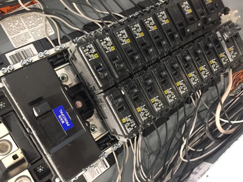 Electrical panel with multiple circuit breakers and wiring, illustrating signs of electrical system management and potential upgrade needs for safety.